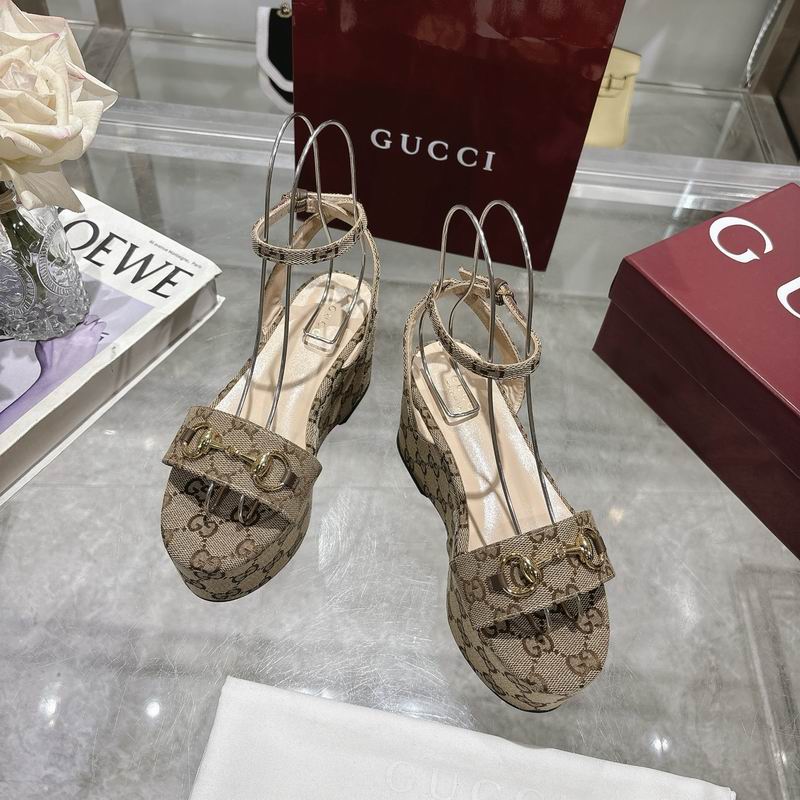 Gucci GG Supreme canvas Horsebit wedge sandals with gold-tone hardware and ankle strap closure, displayed on a glass surface with Gucci branded packaging